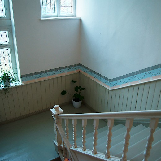 Die schöne alte Treppe begleitet ein zartfarbiger Wandfries passend zur Decken- und Wandgestaltung des Hauses